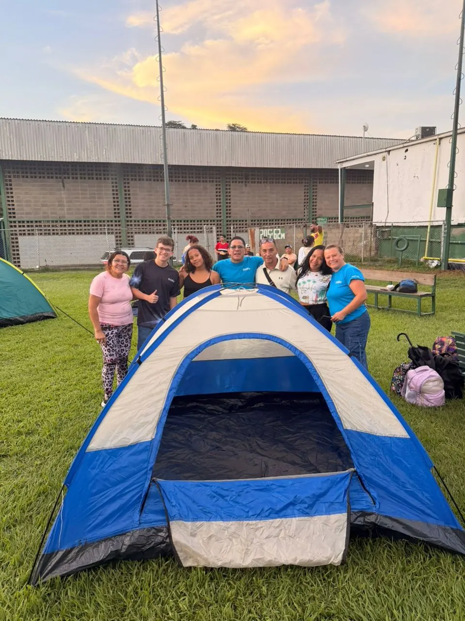 Carpa montada al atardecer, con el equipo y las familias en terreno